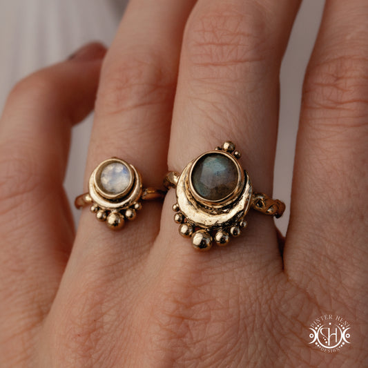 Handmade crescent moon ring with round moonstone set inside the lunar curve, worn on hand.