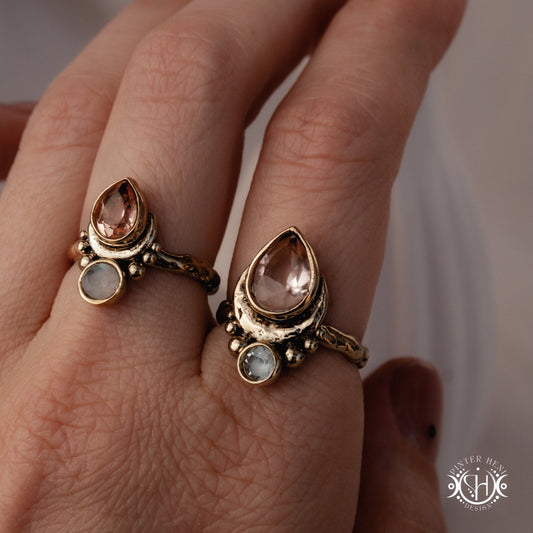 Handmade teardrop rings with morganite, moonstone and aquamarine set in crescent-inspired form, worn on hand