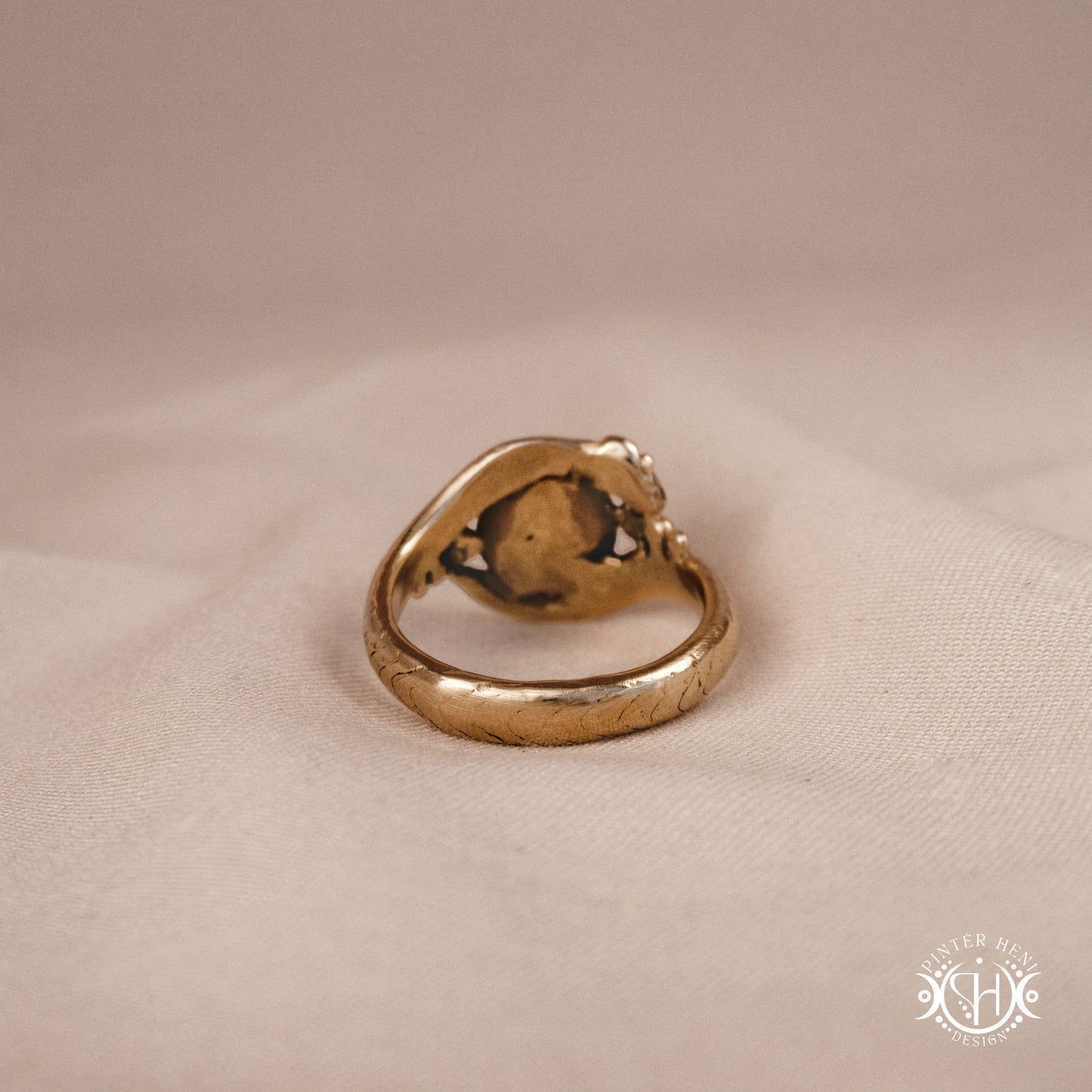 Handmade serpent ring set with moonstone, sculptural wax carved design in brass, silver, or solid gold, back view, on a beige textil.
