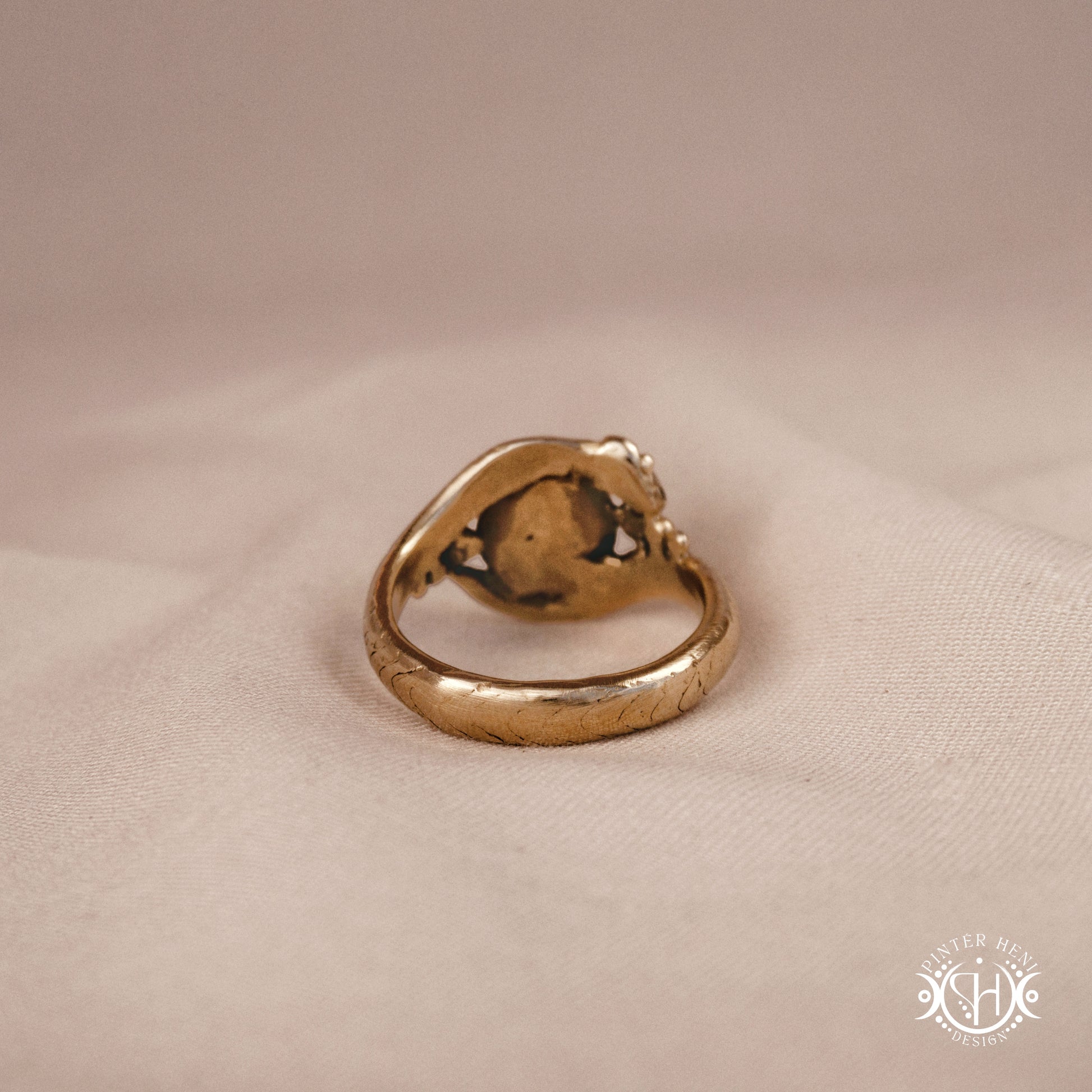 Handmade serpent ring set with moonstone, sculptural wax carved design in brass, silver, or solid gold, back view, on a beige textil.