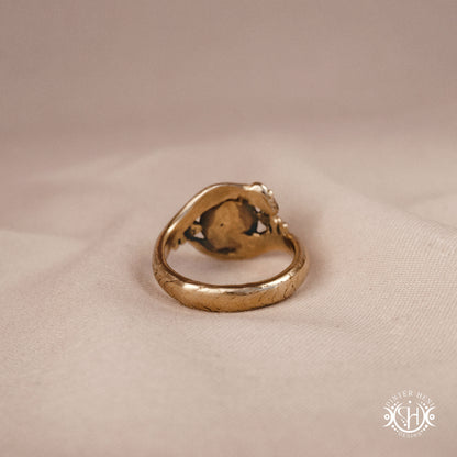Handmade serpent ring set with moonstone, sculptural wax carved design in brass, silver, or solid gold, back view, on a beige textil.