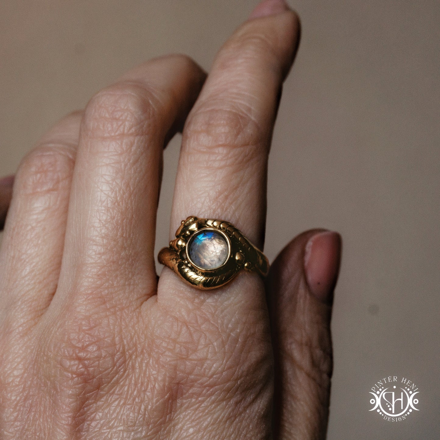 Handmade serpent ring set with moonstone, sculptural wax carved design in brass, worn on hand.
