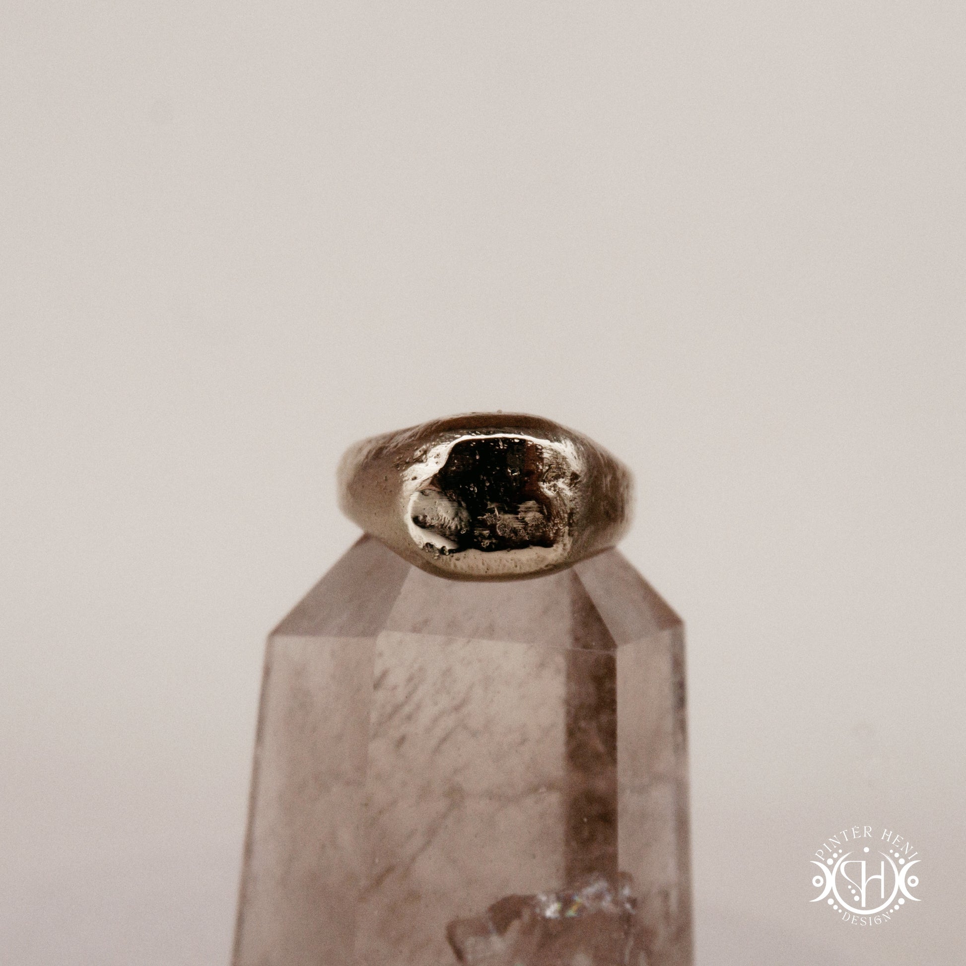 Sigil Ring handmade sandcast brass signet-style ring with raw surface and ancient-inspired sculptural form, in sand.