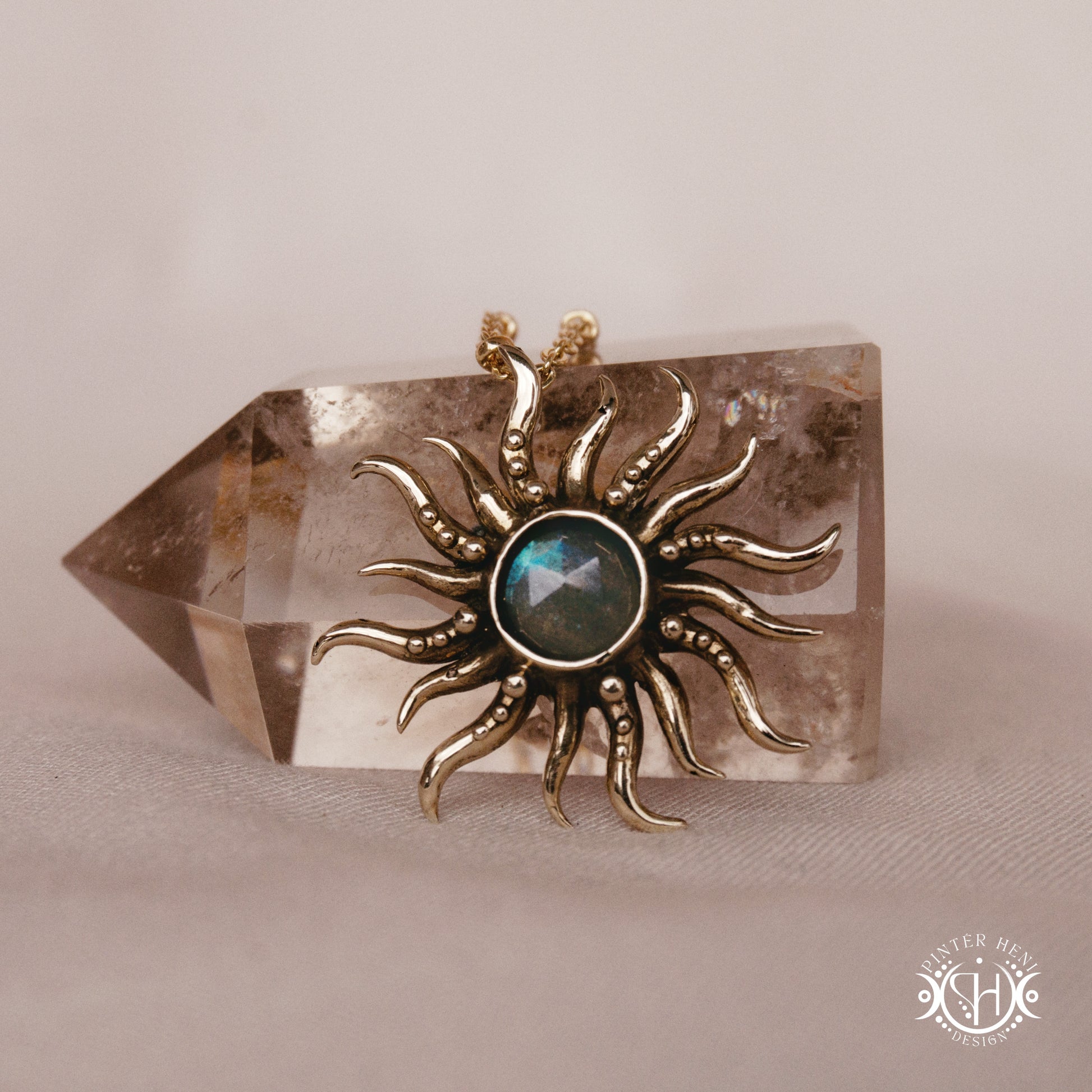 Hand-carved sun pendant in brass with organic rays from the Primal Symbols collection, on a crystal