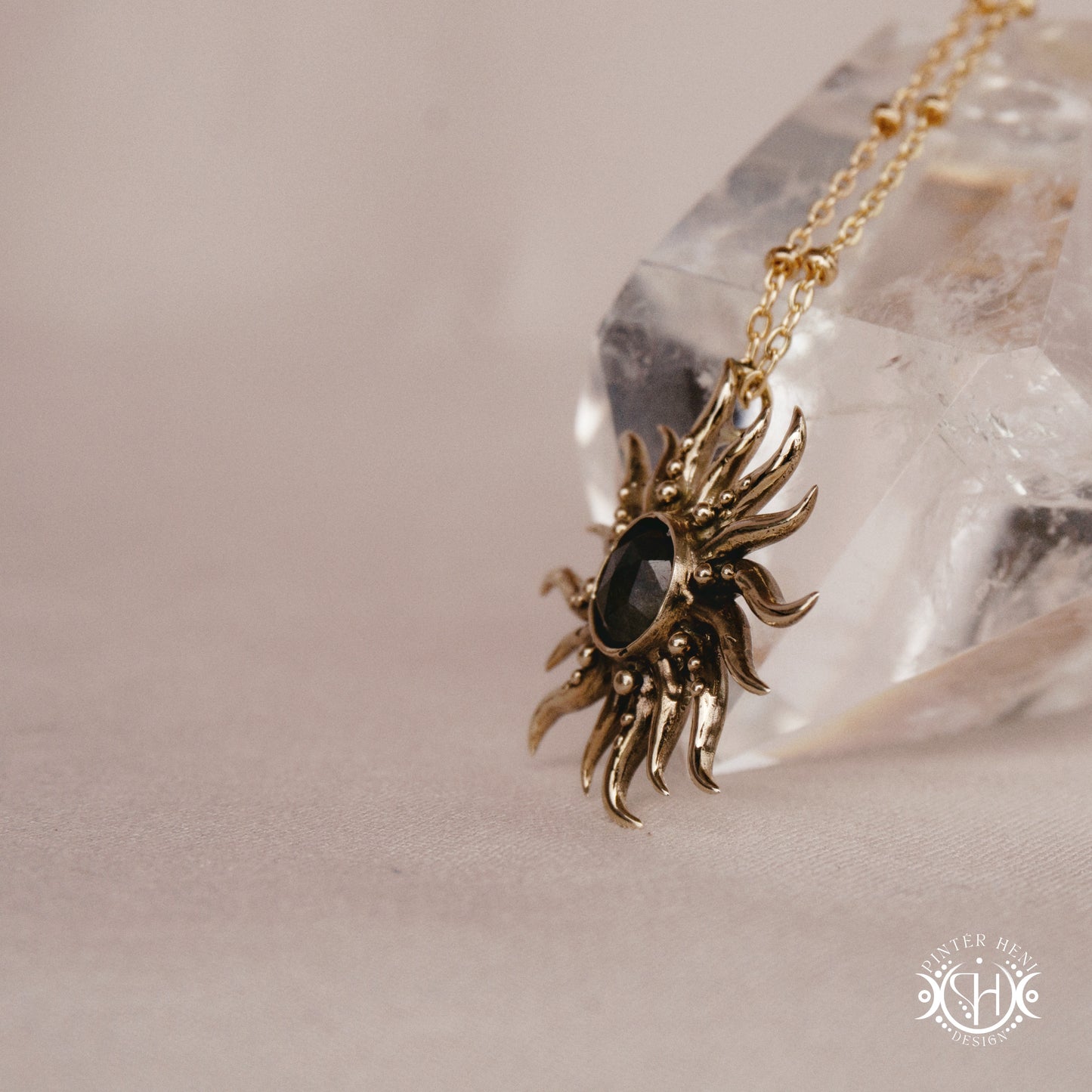 Hand-carved sun pendant in brass with organic rays from the Primal Symbols collection, side view, on a crystal