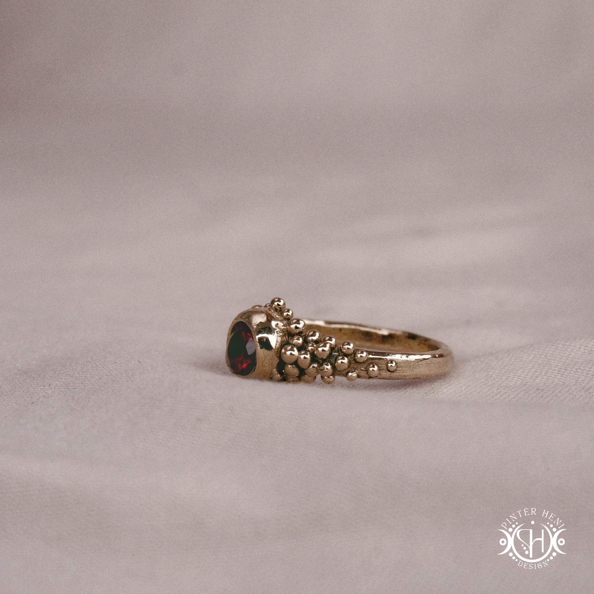 Supernova Core Ring with garnet and clustered bead texture forming an upper arc in handcrafted metal