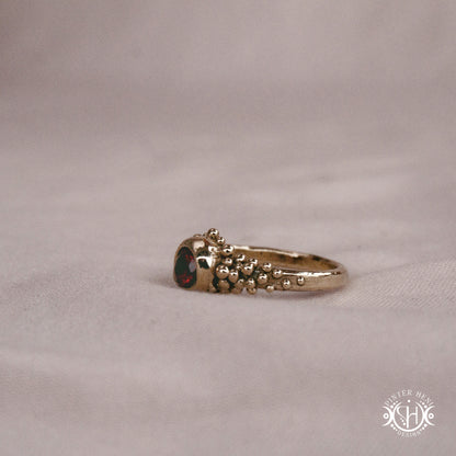 Supernova Core Ring with garnet and clustered bead texture forming an upper arc in handcrafted metal