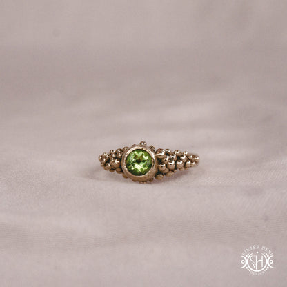 Supernova Core Ring with peridot and clustered bead texture forming an upper arc in handcrafted metal
