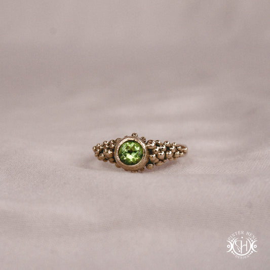 Supernova Core Ring with peridot and clustered bead texture forming an upper arc in handcrafted metal