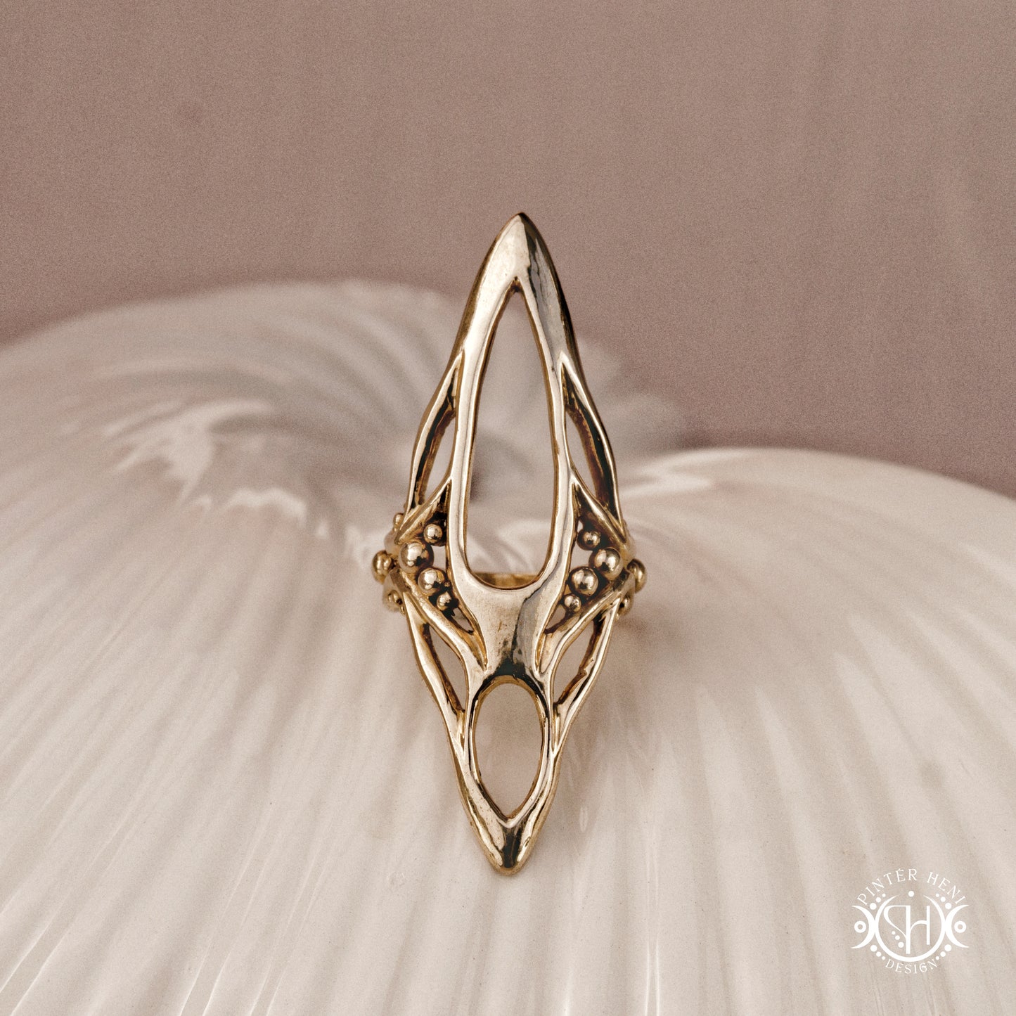 Zenith Ring sculptural vertical axial statement ring in brass, organic elongated handmade design, on ceramic surface