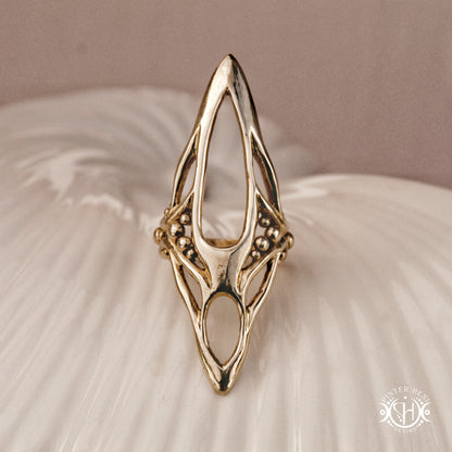 Zenith Ring sculptural vertical axial statement ring in brass, organic elongated handmade design, on ceramic surface.